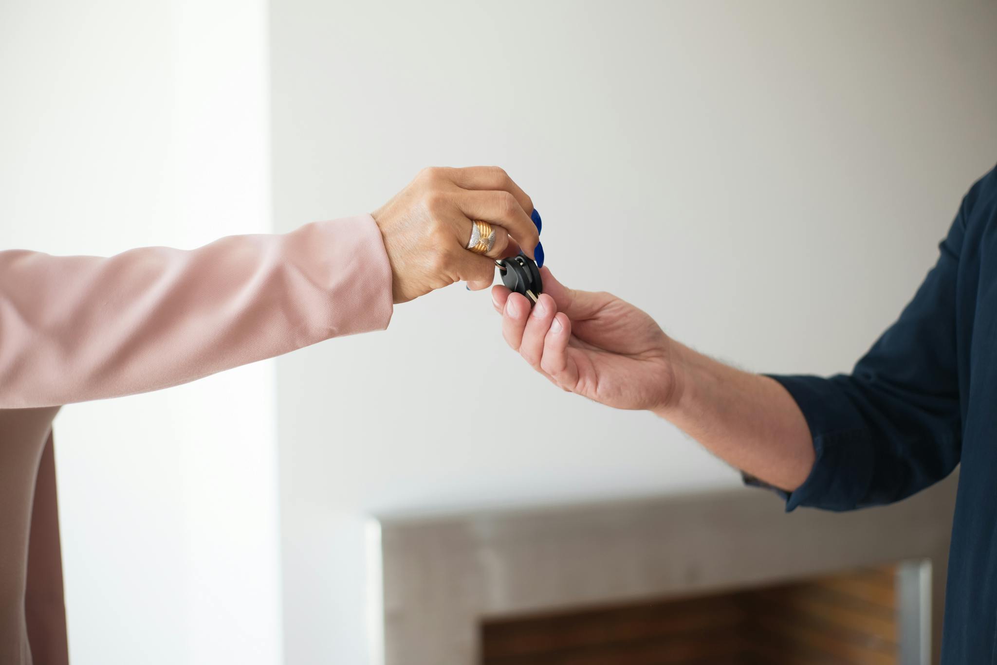 A close-up photo depicting the exchange of keys between two adults, symbolizing a real estate transaction.